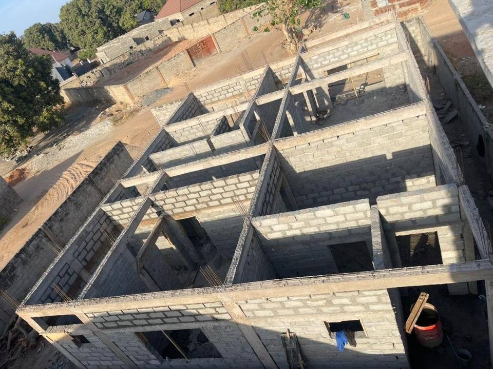 Looking down over the ground-floor blockwork at Jabang, the room divisions laid out and the concrete ring beam cast along the tops of the walls.