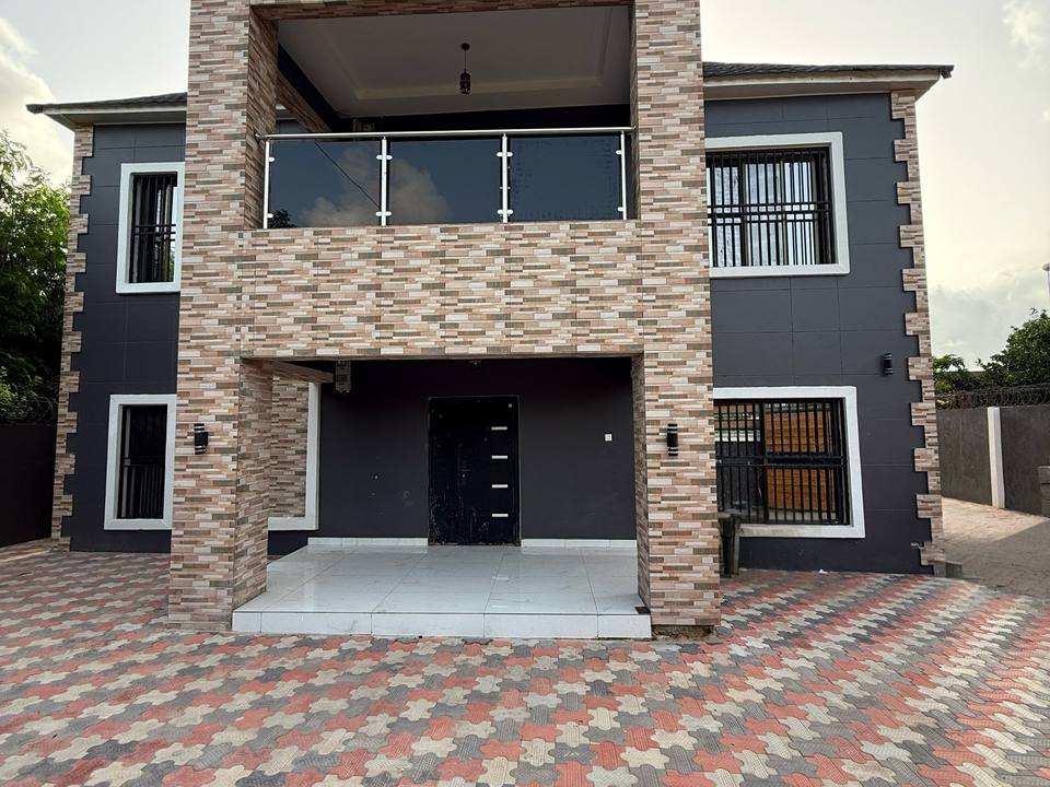 The front facade of the completed two-storey Kololi residence, with a stone-clad entrance bay rising through both floors.
