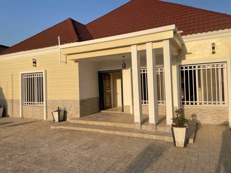 The entrance porch of the Kotu Silo residence, carried on rendered columns with a tiled floor and a panelled front door.
