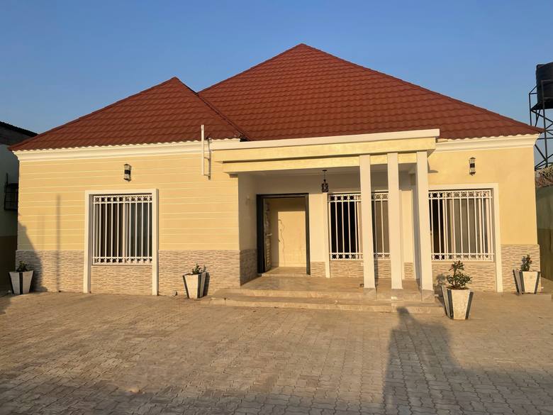 The finished house at handover, rendered and painted, with paving laid around the entrance.
