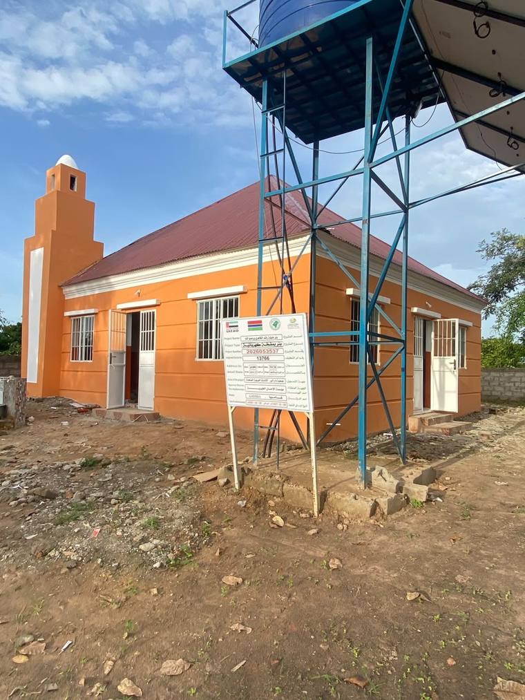 The project signboard on site, recording the mosque as a UAE Aid funded project with its programme reference number.