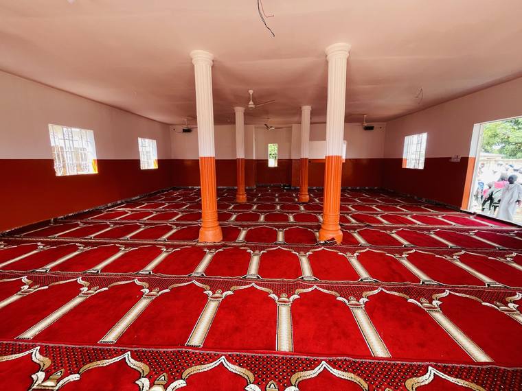 The finished prayer hall, carpeted and fitted out, its rendered columns carrying the roof.