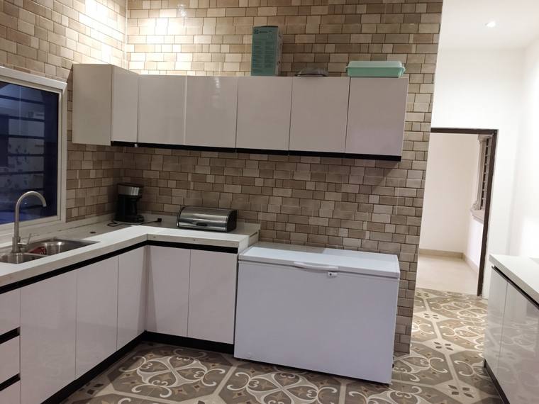 The kitchen from the opposite corner, showing the full run of fitted units and the tiled floor.